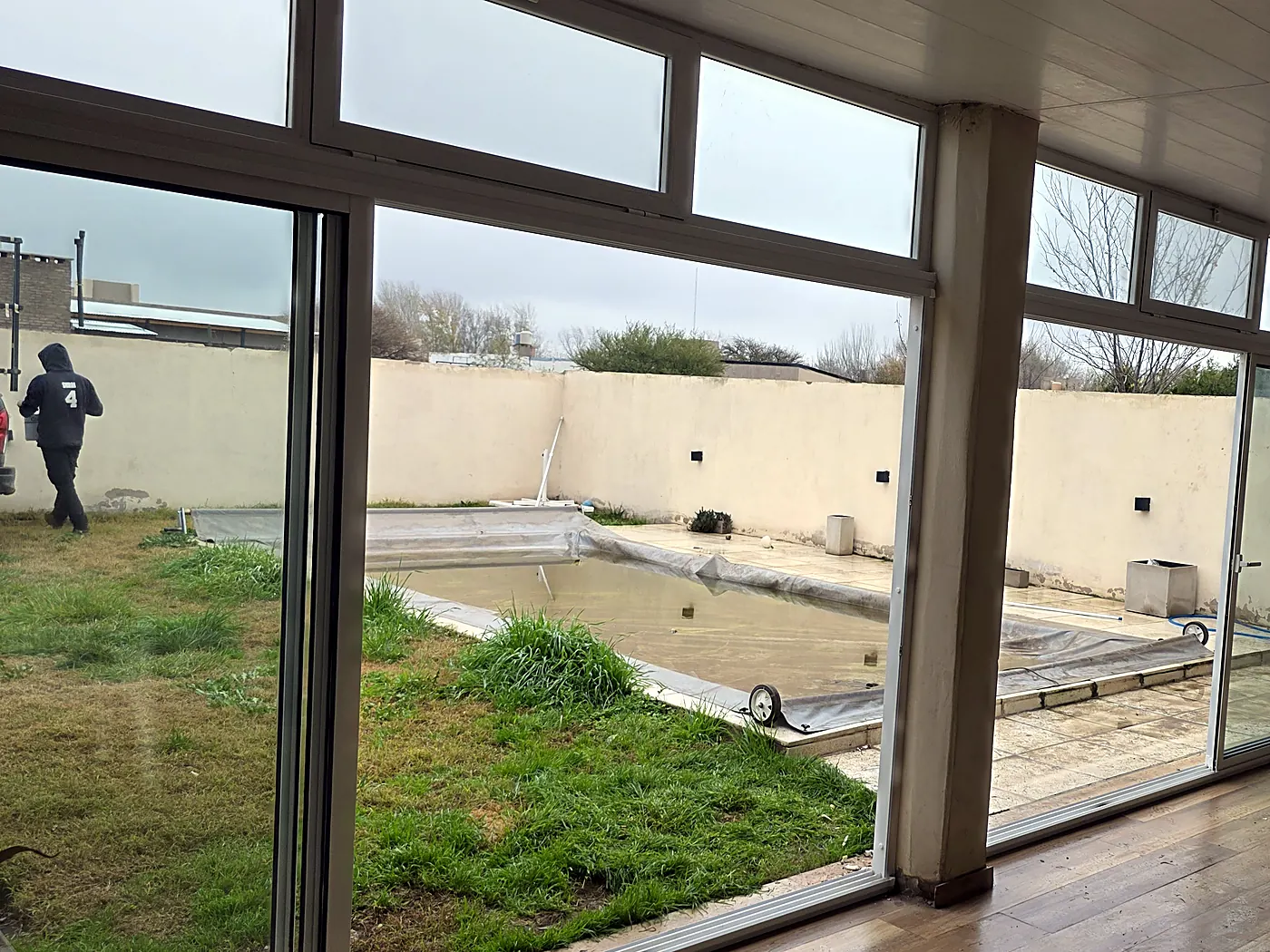 Galería cerrada con aluminio blanco, vista desde adentro hacia el parque y la pileta