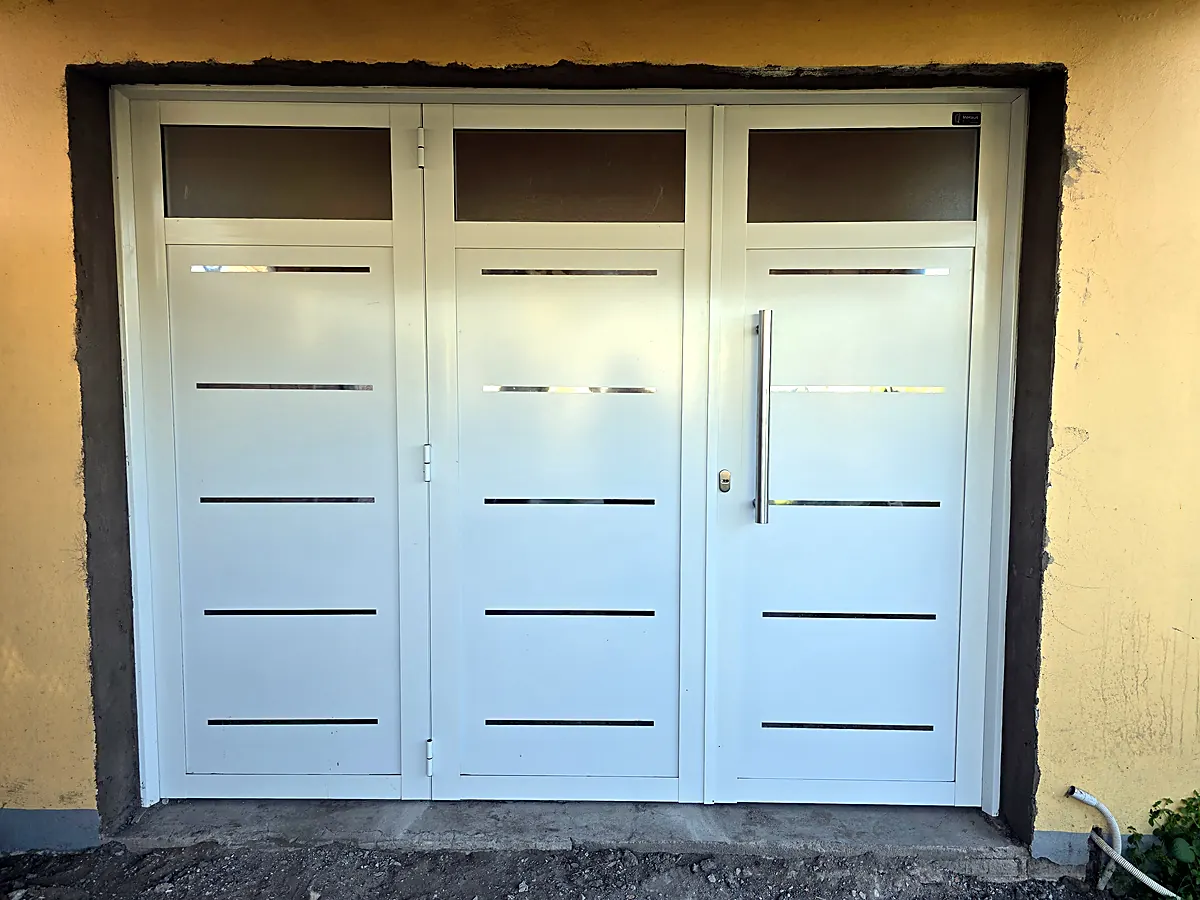 Portón de tres hojas de aluminio blanco, plegadizo, con placa con inserto y manijón