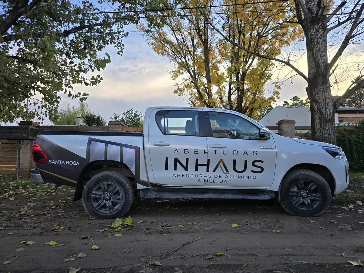 La camioneta de InHaus ploteada con el logo, entera, bajo los árboles
